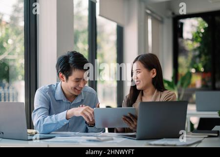 Das Team diskutiert Geschäftsanalysen oder Intelligence Dashboard auf einem digitalen Tablet und diskutiert Diagramme, während es den Vertriebsstandort analysiert. Zwei Analysten Stockfoto