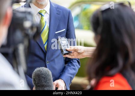 Reporter mit digitalem Voice Recorder und Mikrofon während der Pressekonferenz Oder eine Pressekonferenz mit einer Geschäftsperson Stockfoto