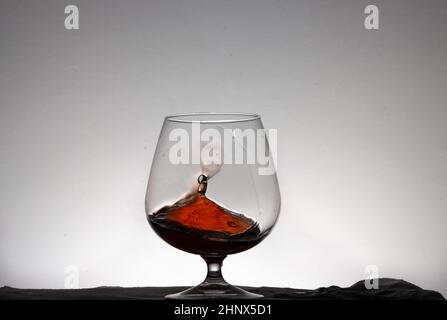 Eine Flasche Wein wird auf weißem Grund ins Glas gegossen Stockfoto