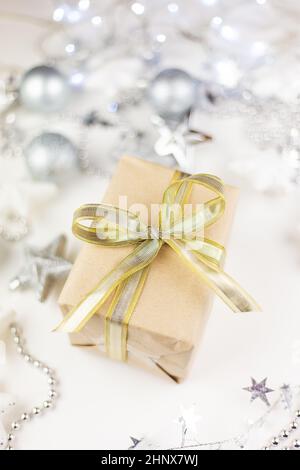 In der Mitte des sortierten Weihnachtsspielzeugs befindet sich eine goldene Geschenkbox aus Kraftpapier auf weißem Hintergrund Stockfoto