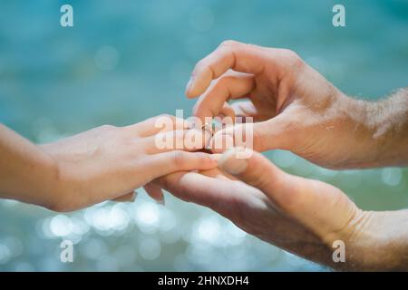Guys Hand legt einem Mädchen einen Ehering auf die Hand Stockfoto