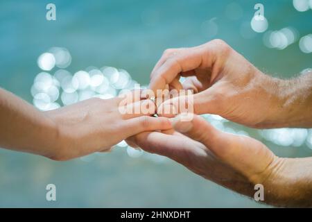 Guys Hand legt einem Mädchen einen Ehering auf die Hand Stockfoto