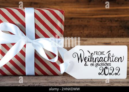 Ein Weihnachtsgeschenk mit Label mit Deutschen Kalligraphie Frohe Weihnachten und ein Glueckliches 2020 bedeutet, frohe Weihnachten und einen guten Rutsch ins Jahr 2020. Verpackung Pap Stockfoto