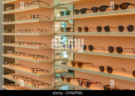 Trendige Sonnenbrillen, Sommerbrillen, Modekollektion, verschiedene Sonnenbrillen auf einem Stand. Brillen Werbeaktionen mit Garantie auf Holzregalen. Niemand Stockfoto