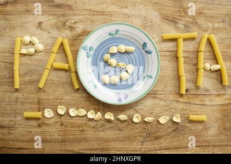 Pasta-Wort mit Nudelkörnern auf Holzhintergrund geschrieben Stockfoto