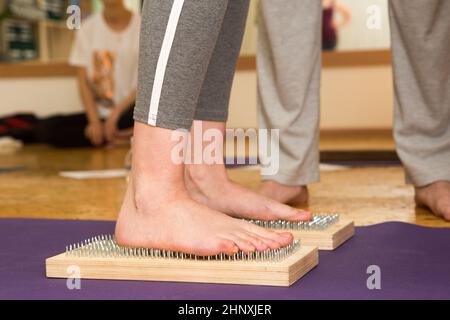 Praxis des Stehens auf Nägeln. Nahaufnahme eines Yoga-Mannes, der auf einem Sadhu-Brett mit scharfen Nägeln steht. Hölzernes Sadhu-Brett mit Nägeln für die Sadhu-Praxis Stockfoto