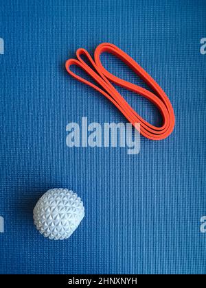 Blaue Kugel und rotes Band auf dem Hintergrund der Trainingsmatte Stockfoto