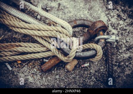 Alter rostiger Metallfestungsring an der Festungswand mit daran gebundenen Seilen. Stockfoto