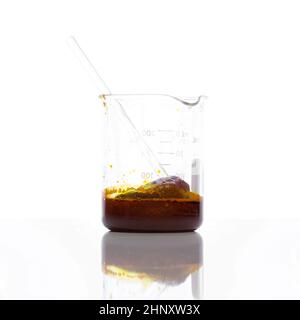 Chemische Zutat aus der Nähe auf weißem Labortisch. Eisenchlorid-Flüssigkeit mit Rührstab im Becher. Seitenansicht Stockfoto