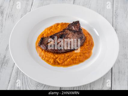 Rindersteak mit Kürbispüree auf weißem Teller Stockfoto