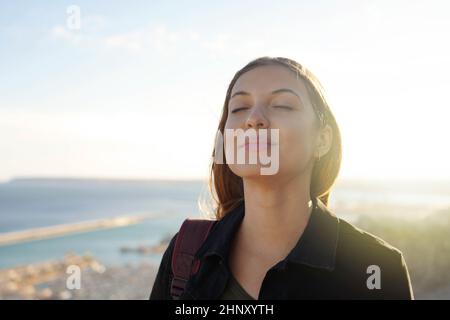 Schöne junge Frau mit geschlossenen Augen atmen entspannend genießen Sonne bei Sonnenuntergang. Schönheit Sonnenschein Mädchen Porträt. Stockfoto