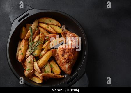 Gebackene Hühnerschenkel Viertel und Schlagstock gewürzt mit Knoblauch und Kräutern mit Kartoffeln in einer Auflaufform Stockfoto