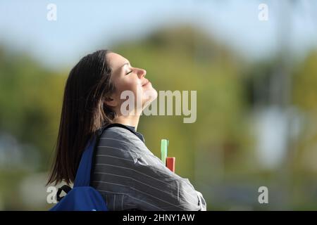 Seitenansicht Porträt eines glücklichen Studenten, der auf einem Campus frische Luft atmet Stockfoto