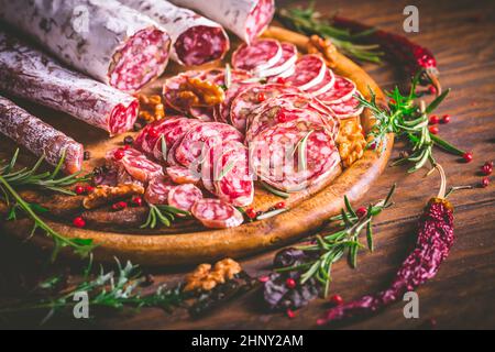 Charcuterie - Sortiment von luftgetrockneten Salami und Wurst auf Holz Schneidebrett mit Gewürzen Stockfoto