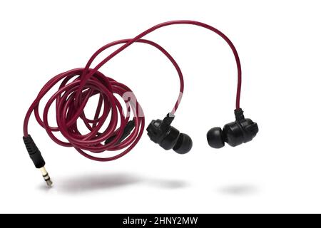 Nahaufnahme von in-Ear-Kopfhörern auf rotem Spiralkabel mit Klinkenstecker als Stecker auf weißem Hintergrund als Konzept zum Hören und Genießen von Musik Stockfoto