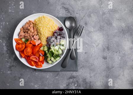 Essen Diät-Konzept, Thunfisch-Salat. Couscous-Salat mit konservierten Thunfisch, Tomaten, Gurken und lila Zwiebeln auf dem Tisch. Speicherplatz kopieren. Stockfoto