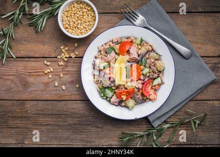Essen Diät-Konzept, Thunfisch-Salat. Couscous-Salat mit konservierten Thunfisch, Tomaten, Gurken und lila Zwiebeln auf dem Tisch. Speicherplatz kopieren. Stockfoto