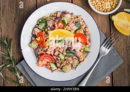 Essen Diät-Konzept, Thunfisch-Salat. Couscous-Salat mit konservierten Thunfisch, Tomaten, Gurken und lila Zwiebeln auf dem Tisch. Speicherplatz kopieren. Stockfoto