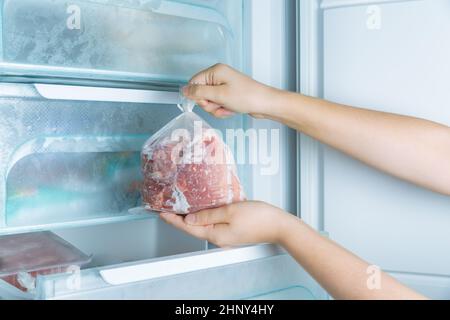 Gefrorenes Fleisch aus dem modernen No-Frost-Gefrierschrank nehmen Stockfoto