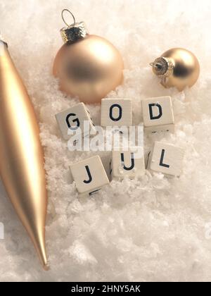 Holzklötze mit Gott Jul, Skandinavien Frohe Weihnachten im Schnee mit goldenen Weihnachtskugeln Stockfoto