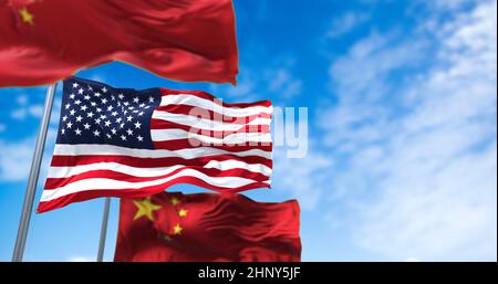 Die Nationalflagge der Vereinigten Staaten winkt zwischen zwei Flaggen Chinas mit klarem Himmel im Hintergrund. Internationale Beziehungen und Diplomatie. Stockfoto