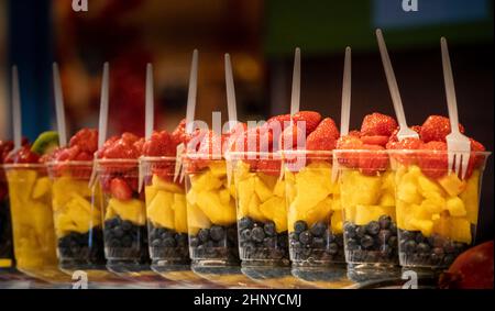 Gemischter Obstsalat arrangiert in Plastikbechern an einem Marktstand. Stockfoto