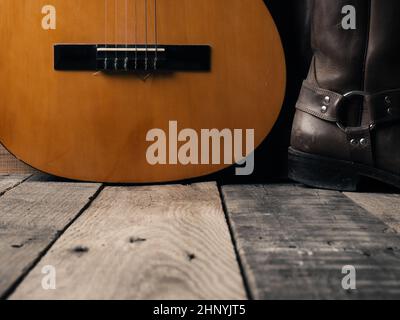 Alte Cowboystiefel mit einer akustischen Gitarre auf Scheunenholz, Platz für Ihren Text Stockfoto