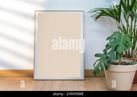 Boho Holzrahmen vertikale Monographie Mockup auf sauberen weißen Wänden, Pflanzen und Sonnenstrahlen. Stockfoto