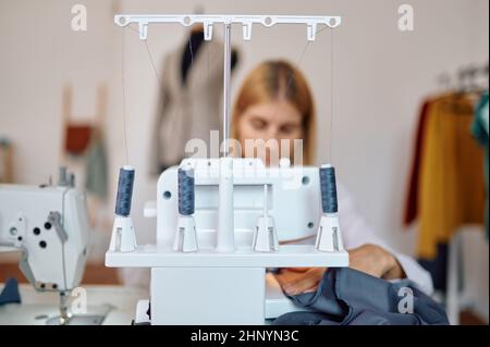 Schneiderin arbeitet an der Nähmaschine an ihrem Arbeitsplatz in der Werkstatt. Schneiderei Beruf, handgemachte Schneiderei Geschäft, Handwerk Hobby Stockfoto