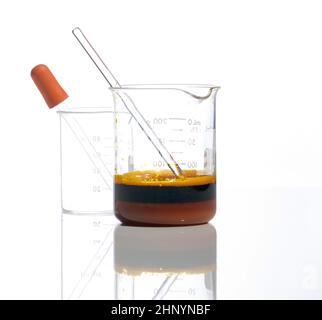Chemische Zutat aus der Nähe auf weißem Labortisch. Eisenchlorid-Flüssigkeit mit Rührstab im Becher. Seitenansicht Stockfoto