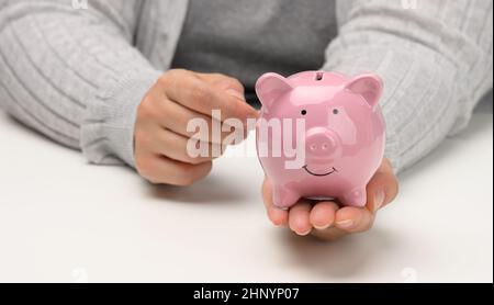 Weibliche Hände halten ein rosa Keramikschwein. Akkumulationskonzept, Budgetkontrolle Stockfoto