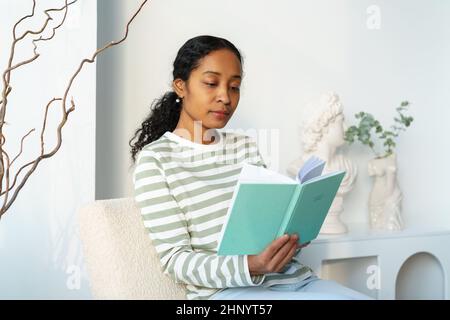 afroamerikanische Frau, die in ihrer Freizeit friedlich Buch liest. Digitale Entgiftung. Langsamer Lebensstil Stockfoto