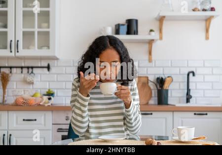 afroamerikanische Frau mit langem Covid-Syndrom. Konzept für den Geruchverlust. Es gab keinen Kaffeegeschmack Stockfoto