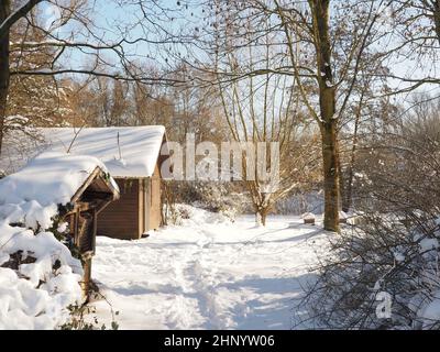 Holzhütte in einem Stück Wald, nach starkem Schneefall mit Schnee bedeckt, Bienenstöcke im Hintergrund, saisonaler Hintergrund Stockfoto