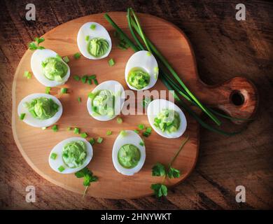 Gefüllte deviled Eggs Vorspeise mit Avocado und Lauch auf Schneidebrett. Draufsicht. Stockfoto