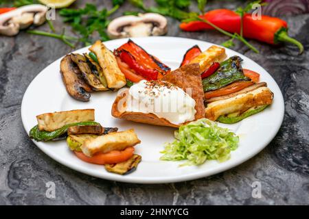 Gegrilltes Gemüse mit Halloumi-Käse auf einem weißen Porzellanteller Stockfoto
