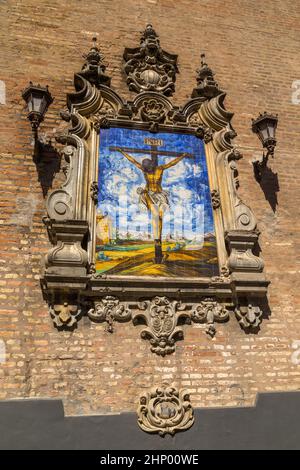 Azulejo zeigt Jesus am Kreuz auf einer Außenwand der Kirche der Verkündigung (Iglesia de la Anunciacion) in Sevilla, Spanien. Die Kirche in R Stockfoto