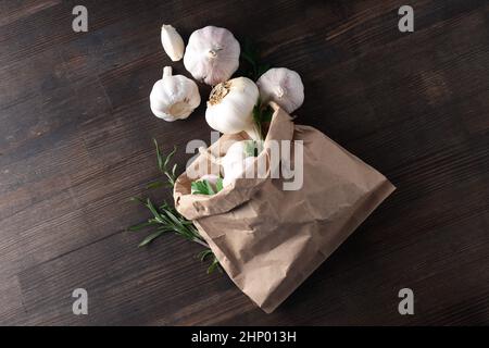 Papiertüte mit Knoblauch, Petersilie und Rosmarin auf Holzgrund Stockfoto