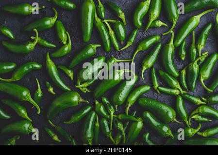 Draufsicht auf Green Jalapeno Peppers auf schwarzem Beton Hintergrund Stockfoto