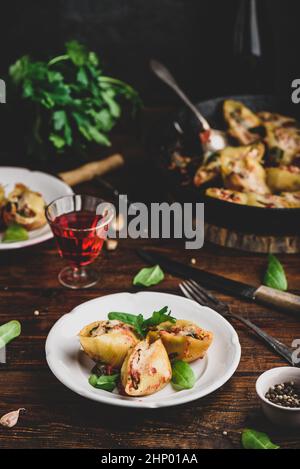 Gebackene Schalen Pasta gefüllt mit Hackfleisch, Spinat und Käse auf weißem Teller Stockfoto