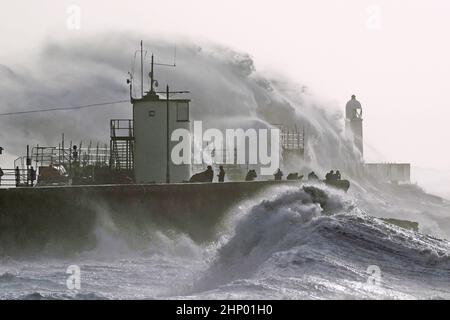 Die Wellen stürzen gegen die Meeresmauer und den Porthcawl Lighthouse in Porthcawl, Bridgend, Wales, ab, als der Sturm Eunice die Südküste trifft, wobei die Attraktionen schließen, die Reise gestört wird und in einigen Gebieten ein größerer Vorfall gemeldet wird, was bedeutet, dass die Menschen gewarnt werden, drinnen zu bleiben. Bilddatum: Freitag, 18. Februar 2022. Stockfoto