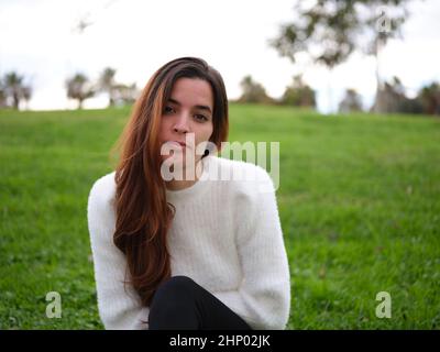 Eine verspottete junge Frau im Park, die ernsthaft die Kamera ansah Stockfoto