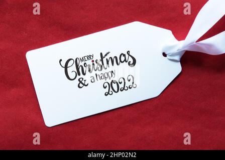 Label mit englischer Kalligraphie Frohe Weihnachten und Ein Happy 2022. Roter Strukturierter Hintergrund Stockfoto