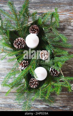 Einfache weihnachtliche Blumenarrangements für einen festlichen Tisch aus Tannenzweigen, Kerzen und Zapfen Stockfoto