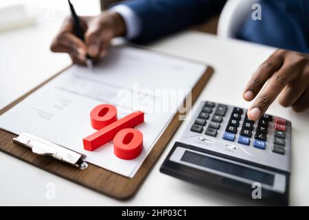 Rotes Prozentsymbol Vor Dem Unternehmer, Der Die Rechnung Berechnet Stockfoto