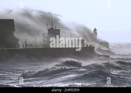 Die Wellen stürzen gegen die Meeresmauer und den Porthcawl Lighthouse in Porthcawl, Bridgend, Wales, ab, als der Sturm Eunice die Südküste trifft, wobei die Attraktionen schließen, die Reise gestört wird und in einigen Gebieten ein größerer Vorfall gemeldet wird, was bedeutet, dass die Menschen gewarnt werden, drinnen zu bleiben. Bilddatum: Freitag, 18. Februar 2022. Stockfoto