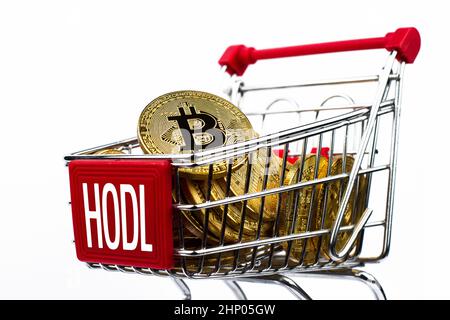 Seitenansicht Nahaufnahme Kryptowährung Konzept des Markteinkaufswagens voller Bitcoin-Goldmünzen mit Wort-Hodl auf der Vorderseite isoliert auf Weiß Stockfoto