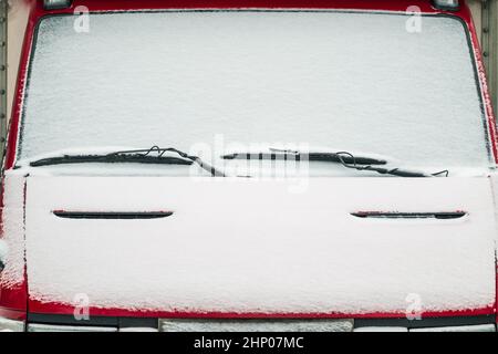 Die Windschutzscheibe des Autos mit Schnee bedeckt. Scheibenwischer sind wie Augenbrauen über den Augen. Stockfoto