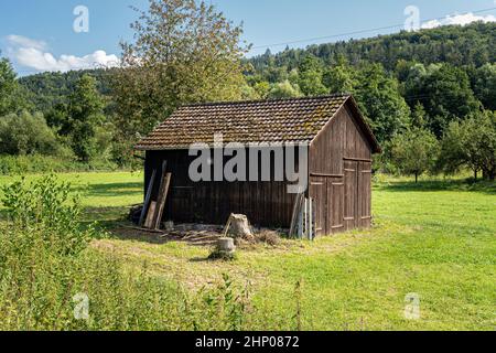 Holzgartenschuppen in der Mitte einer grünen Wiese Stockfoto