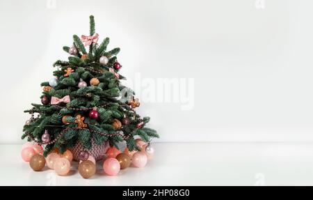 Schöner kleiner geschmückter Weihnachtsbaum auf einem weißen Holztisch. Gut gelaunt. Dänische Kiefer und Tanne, Nobilis Stockfoto